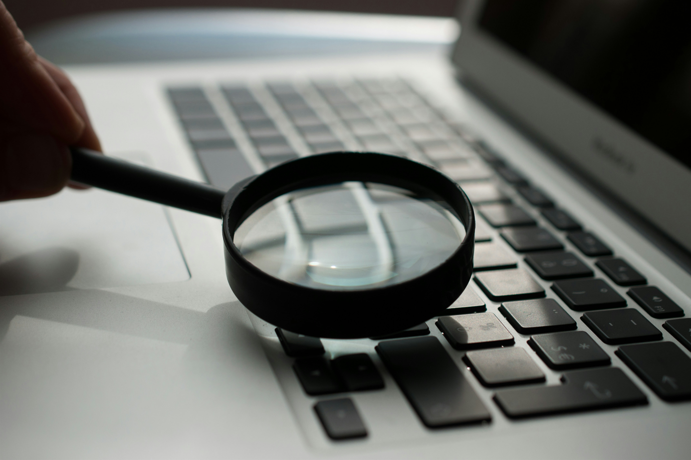 A magifying glass resting on a laptop keyboard